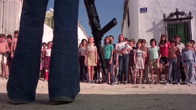 Imagen de ¿Quién puede matar a un niño? Es una fila de niños que están enfrente de una persona con una arma larga. 